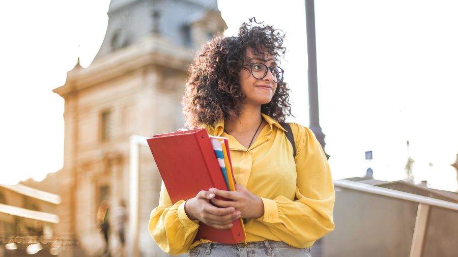 Girl holding books walking on campus