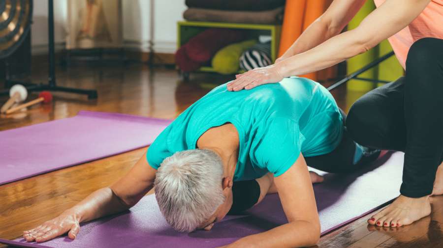 Physical therapist assisting older client during a stretch